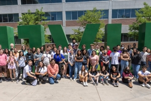 A crowd of students in front of a sculpture that spells UVU