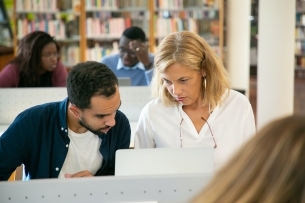 An instructor works with a student using a computer.