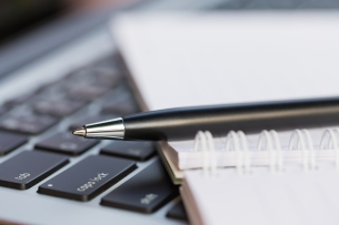 Close, cropped photo of a notebook open on top of a laptop keyboard.