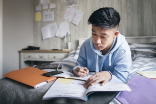 A student lying on his bed studying