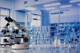 A scientific laboratory, featuring a microscope in the foreground and lots of glassware in the background.