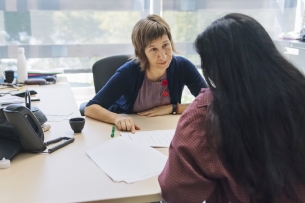 A college counselor meets with a young female student in her office.