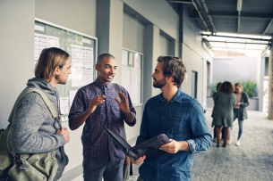 Three male college students talk in a hallway.