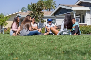 A group of students sits on a lawn at California Baptist University