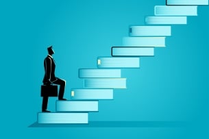 Man with a briefcase walks up a staircase of books