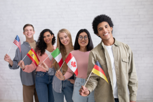 A group of five college-aged students holding flags from five different nations.