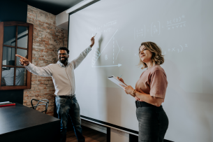 Two professors teach math at the front of the classroom.