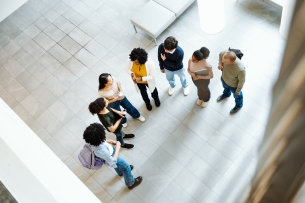 Group of diverse students gathered around a professor and talking