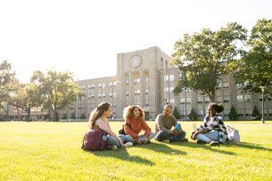 University students hanging out on campus main lawn on a sunny day