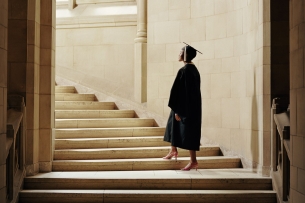 A woman in a cap and gown going up the stairs