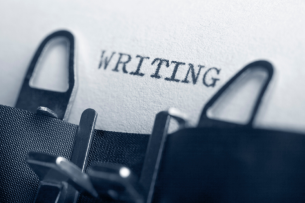 The top of a typewriter and a piece of paper with the typed word "WRITING."