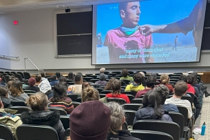 An auditorium of students watching a film