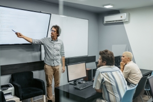 Young male teacher teaching young students a programming class in the classroom.