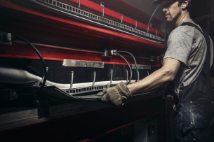 Man in work gear crafts a snowboard by hand.