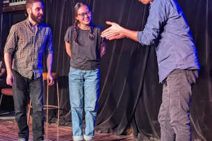 Three students play an improv game on stage.