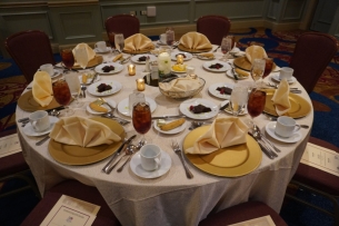 A formal dinner setting with multiple silverware, glasses and linen napkins