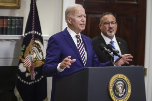 President Biden standing at a podium with Education Secretary Miguel Cardo on his left.na