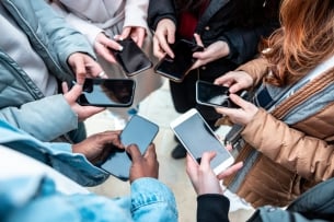 A group of people hold their cellphones in a circle