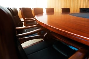 A photo of chairs around a sleek conference table.