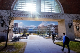 Sunlight filters through an pedestrian bridge at the University of Kentucky campus as several student walk below it.
