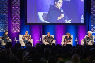 A panel of five individuals sitting on a stage.