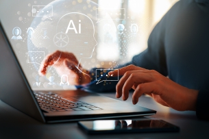 A close-up of a student’s hands on a laptop keyboard with icons relating to AI seeming to emanate from the computer.