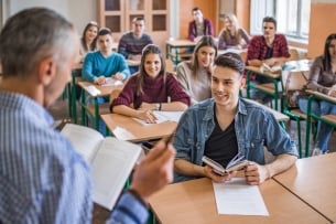 Man reading a book to a class in which students are smiling and engaged