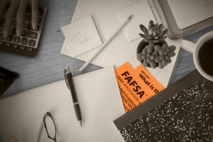 FAFSA forms buried under other items on a messy desk. 