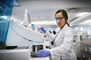 A female scientist wearing protective clothing and eyewear while working in a lab