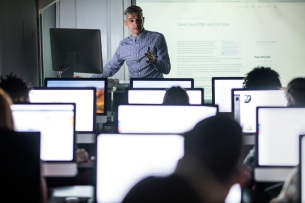 Adult male teacher teaching student during a class at computer lab