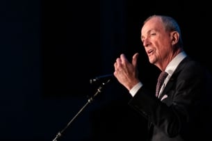 Phil Murphy gesticulates in front of a microphone. 