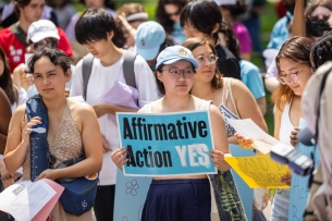 A student with a hat and a sign that says “affirmative action yes” in a crowd
