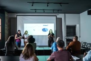 Three women present charts to a classroom