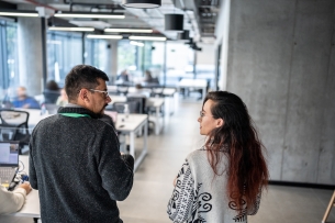 An older professional walks alongside a younger intern through the office