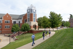 People walk up a sidewalk next to a brick building