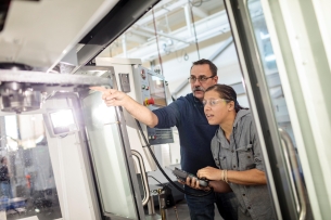 A student works with an instructor on a machine