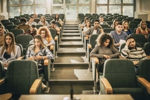 A group of bored, disengaged-seeming college students in a lecture hall.