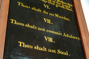 A chalkboard-like surface displays three of the Ten Commandments—"VI Thou shalt do no Murder, VII Thou shalt not commit Adultery, VIII Thou shalt not Steal."