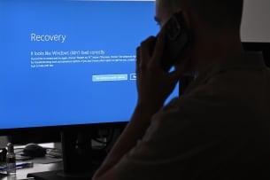 A person talking on the phone in front of a blue error screen