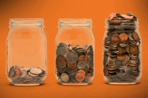 An image of three coin jars, each filled with a larger amount of coins from left to right. 