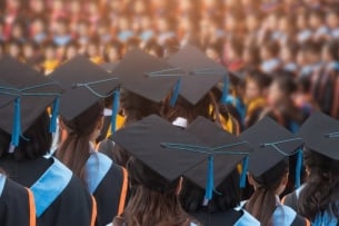 Graduates wearing commencement regalia with their backs to the camera