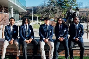 Five young men in blue blazers smile for a photo on the University of Missouri at Kansas City campus