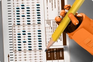 An orange robot hand holds a pencil over a standardized test. The test has bubbles filled in spelling out "A" and "I"