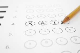 A multiple-choice test answer sheet with the letters "S," "A" and "T" prominently featured in bubbles (instead of the traditional "A," "B," "C," and "D" choices). A sharpened No. 2 pencil lies on top of the answer sheet.