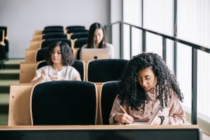 A lecture hall with three students sitting at desks