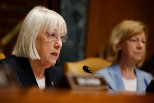 Senator Patty Murray sits behind a microphone 