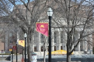 A college campus glimpsed through bare tree branches.