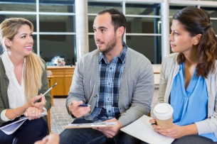 Three students sit in a row engaging in conversation with each other