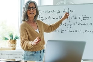 Teacher at whiteboard with math problems