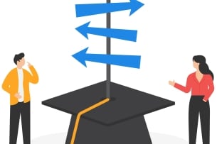 A male and female student stand on either side of a mortarboard with a pole sticking out of it with signs pointing in two different directions